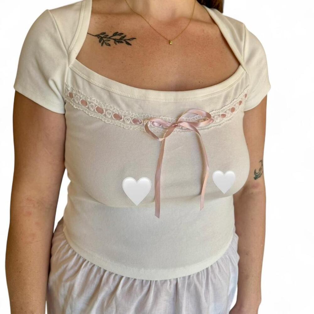 Cream top with pink ribbon accents